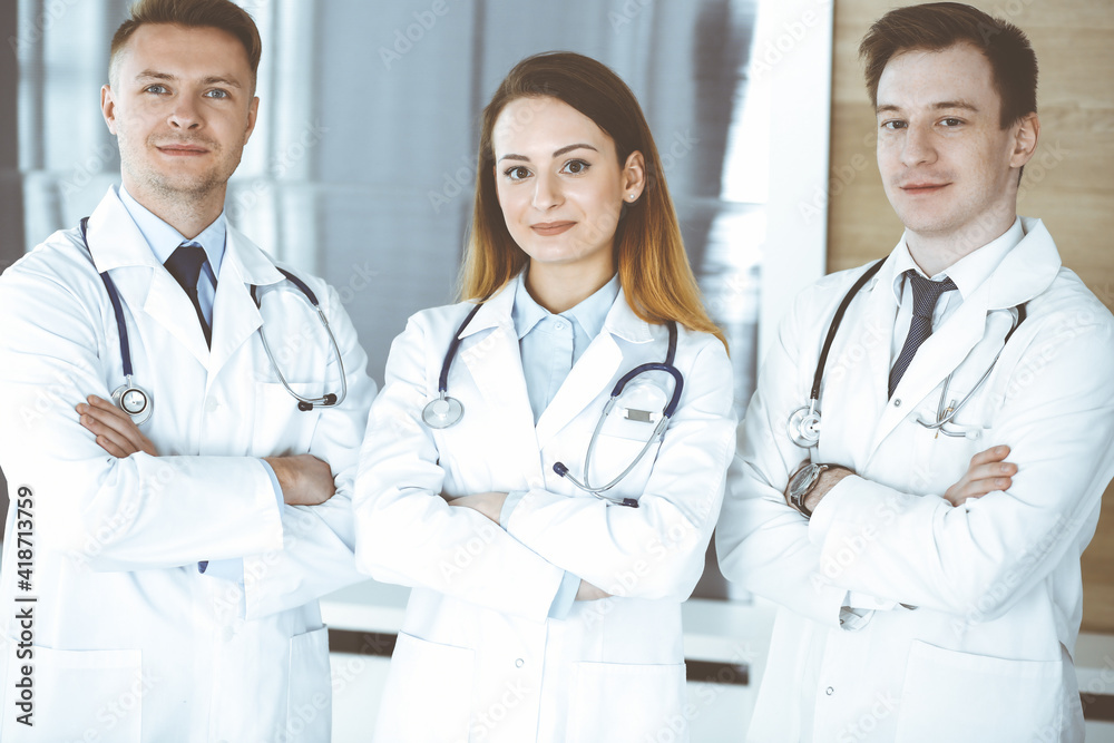 Group of modern doctors standing as a team with arms crossed in hospital office. Physicians ready to examine and help patients. Medical help, insurance in health care, best treatment and medicine Group of modern doctors standing as a team with arms crossed in hospital office. Physicians ready to examine and help patients. Medical help, insurance in health care, best treatment and medicine