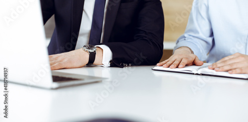 Unknown business people using laptop computer at the desk in modern office. Businessman or male entrepreneur is working with his colleague. Teamwork and partnership concept