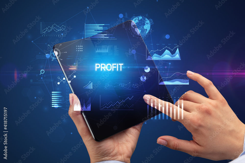 Businessman holding a foldable smartphone with PROFIT inscription, successful business concept Businessman holding a foldable smartphone with PROFIT inscription, successful business concept