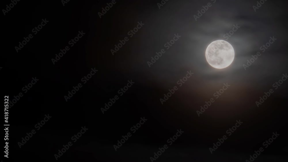 Timelapse - bright full moon rising against black dark sky with fast moving clouds at night. Time lapse, astronomy, mystical, halloween, moonrise and nature concept Timelapse - bright full moon rising against black dark sky with fast moving clouds at night. Time lapse, astronomy, mystical, halloween, moonrise and nature concept