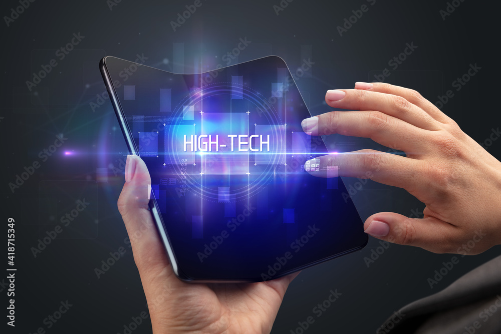Businessman holding a foldable smartphone with HIGH-TECH inscription, new technology concept Businessman holding a foldable smartphone with HIGH-TECH inscription, new technology concept
