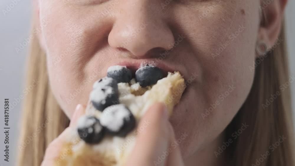 Close-up of white blonde woman eating bakery croissant with soft cheese and blueberry. unrecognizable lady eating her breakfast or lunch deliciously. Close-up of white blonde woman eating bakery croissant with soft cheese and blueberry. unrecognizable lady eating her breakfast or lunch deliciously.