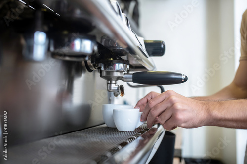 Male hands putting cups into coffee machine