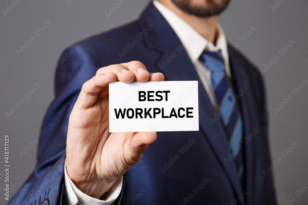 Businessman holding a card with BEST WORKPLACE message, business concept image with blurred focus background. Businessman holding a card with BEST WORKPLACE message, business concept image with blurred focus background.