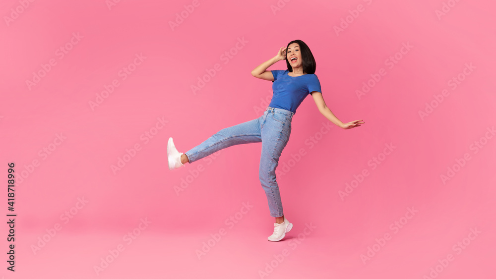 Cheerful young asian lady jumping at studio