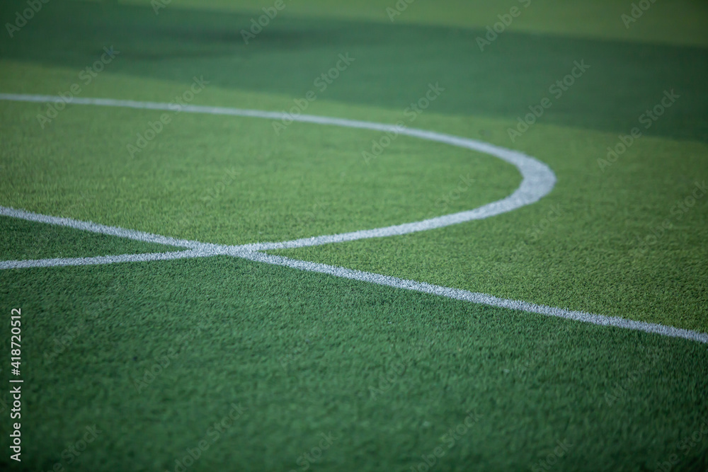 Selective focus to white lines on green artificial grass football fields with kid soccer player. Football or soccer academy.