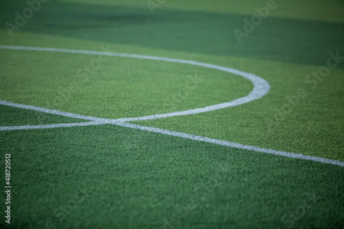 Selective focus to white lines on green artificial grass football fields with kid soccer player. Football or soccer academy.