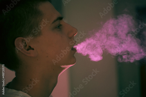 young boy teen smokes, exhales big puffs of smoke