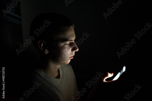 teenager depends on mobile social networks, looks at the phone in the dark