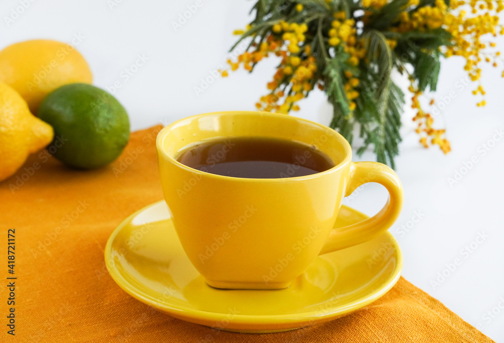 Cup of coffee and vase with blooming branches of mimosa on a white background Cup of coffee and vase with blooming branches of mimosa on a white background