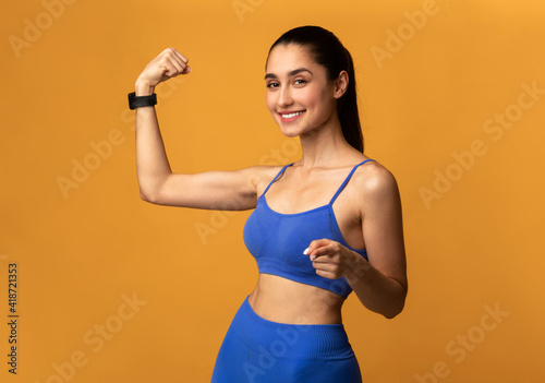 Sporty woman showing biceps and pointing to camera