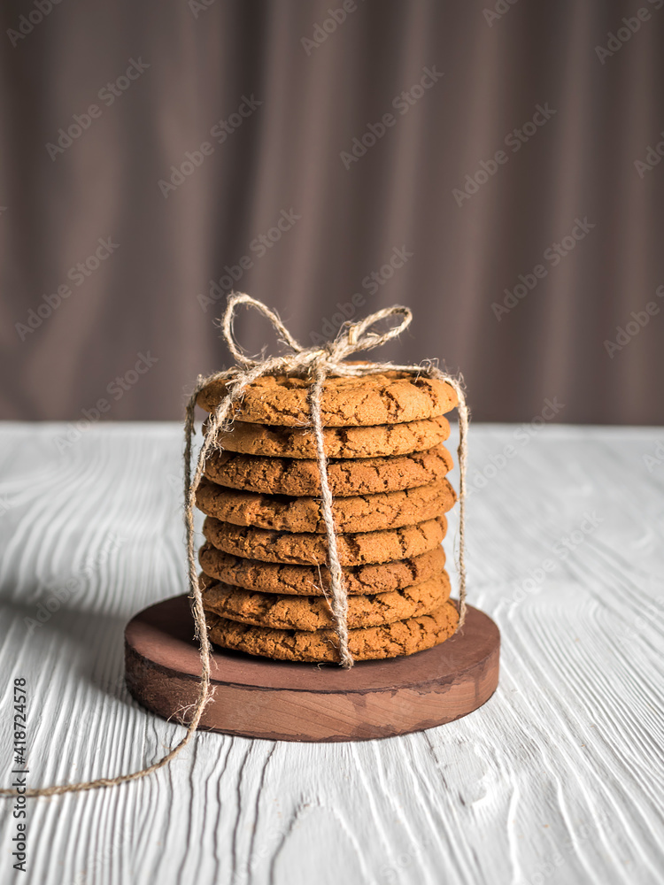 Tied cookies on a stand, on a white wooden background