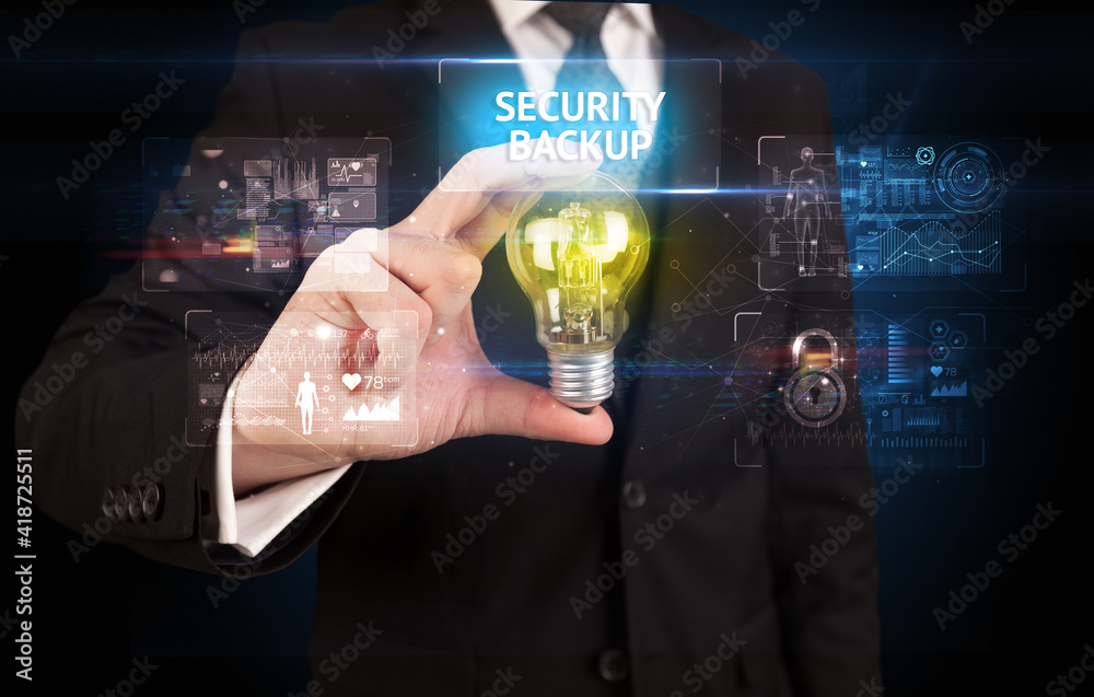 Businessman holding lightbulb with SECURITY BACKUP inscription, online security idea concept Businessman holding lightbulb with SECURITY BACKUP inscription, online security idea concept