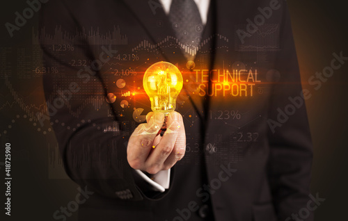 Businessman holding lightbulb with TECHNICAL SUPPORT inscription, Business technology concept