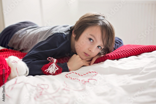 Cute child, blond boy, playing with white and red bracelet photo