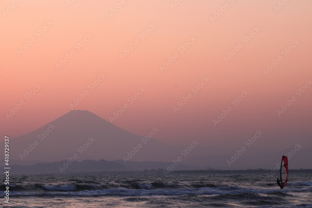 ウィンドサーフィンと夕暮れにかすむ富士山のシルエット