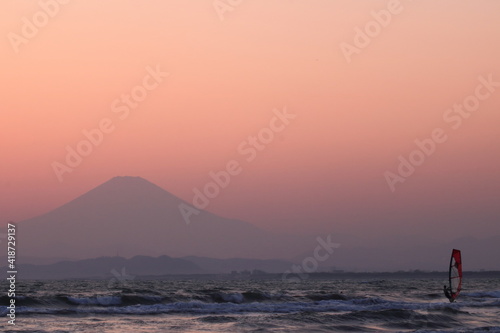 ウィンドサーフィンと夕暮れにかすむ富士山のシルエット