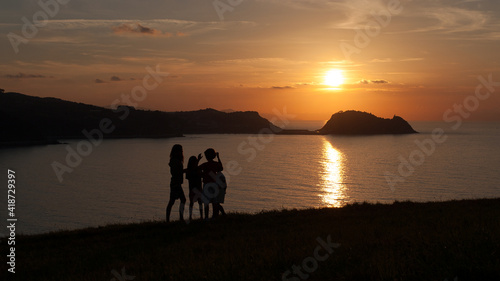 Silhouette of a family at sunset on the coast of Zarautz in the Basque country with the Getaria mouse in the background photo