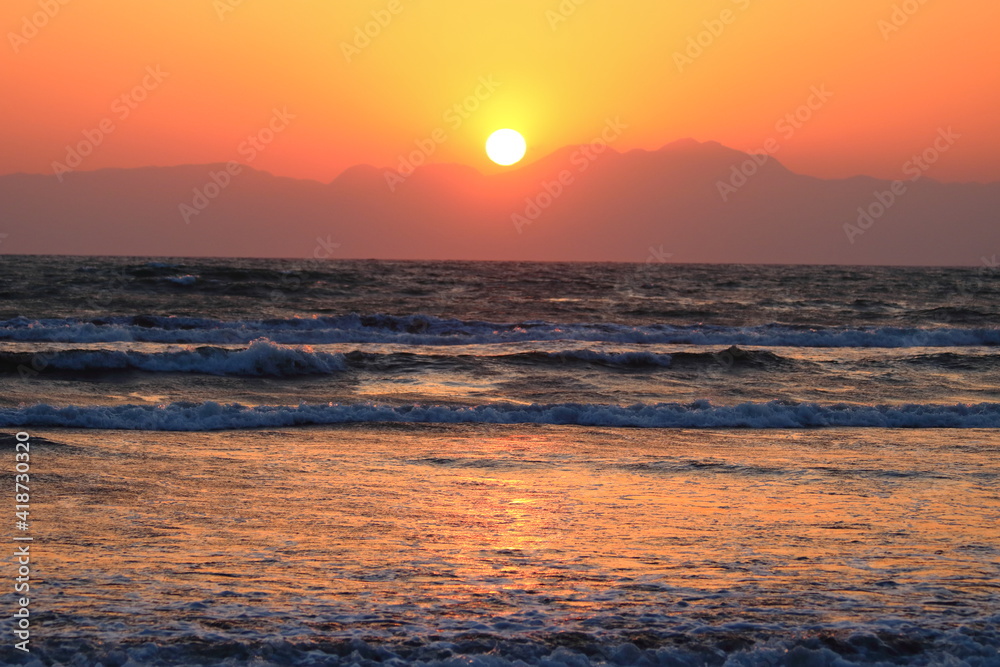 Obraz premium 海岸線から臨む山あいに沈む夕日