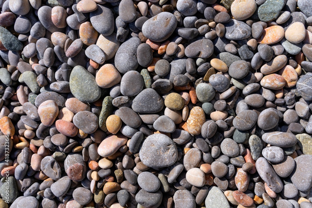 Natural texture of multi-colored oval pebbles that evenly cover the sea beach Natural texture of multi-colored oval pebbles that evenly cover the sea beach