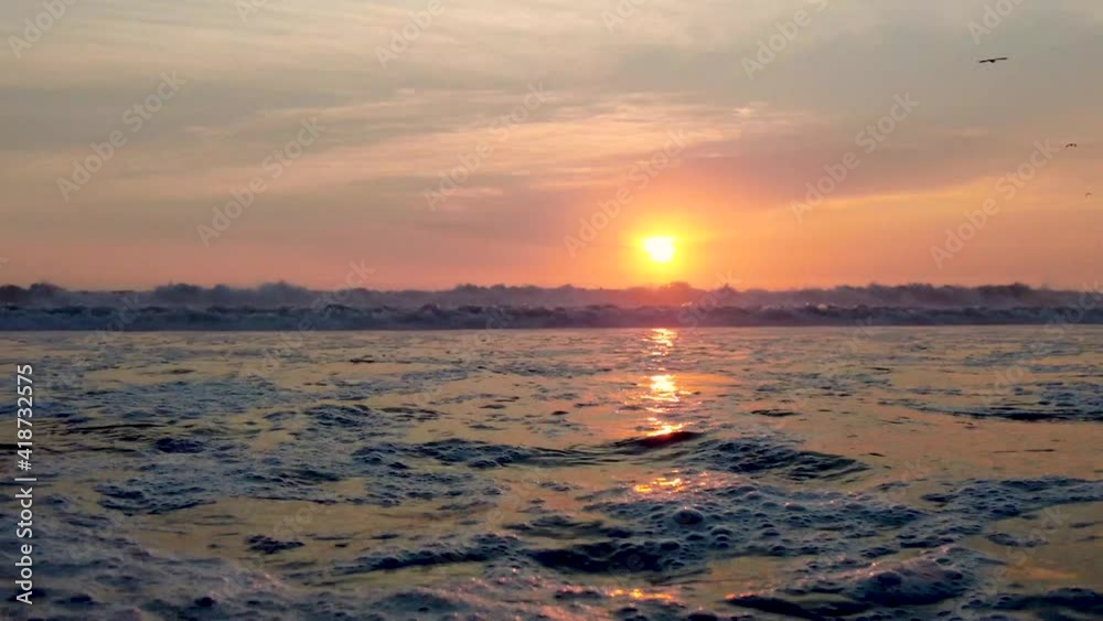 Beautiful Golden Ocean Sunset with waves and birds silhouettes.
