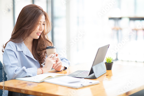 Portrait of Asian Young Female working financial report with tablet at home office.