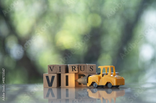 Toy drill car kill to VIRUS text in wooden blocks. Beat virus concept.