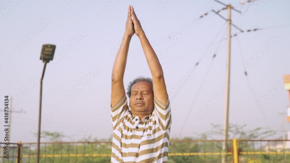 Old man busy doing surya namaskara yoga or exercise during morning - concept of senior people fitness workout and healthcare Old man busy doing surya namaskara yoga or exercise during morning - concept of senior people fitness workout and healthcare