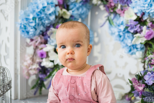 portrait of a baby girl sitting with flowers