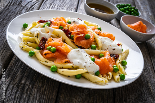 Maccheroni al ferretto with salmon nuggets, peas and sun-dried tomatoes on wooden table
 photo