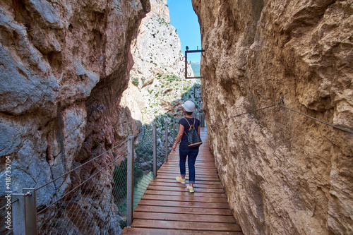 Young girl in Caminito Del Rey - mountain wooden path along steep cliffs in Andalusia, Spain