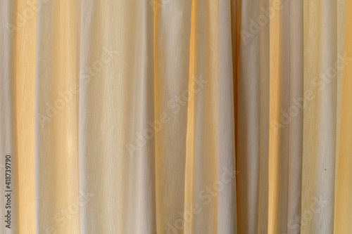 Background of cream curtains backlit by sunlight