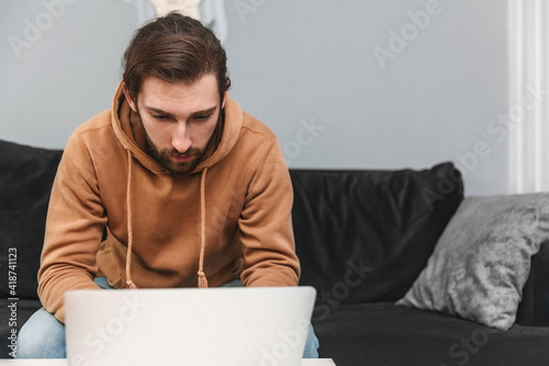 фотографія Focused young man working at home using laptop