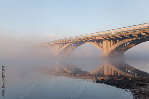 A bridge over a large river.. Fog on the river in early spring
