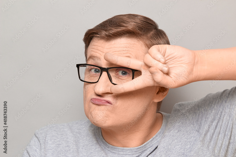 Portrait of funny man showing peace or victory sign near eyes