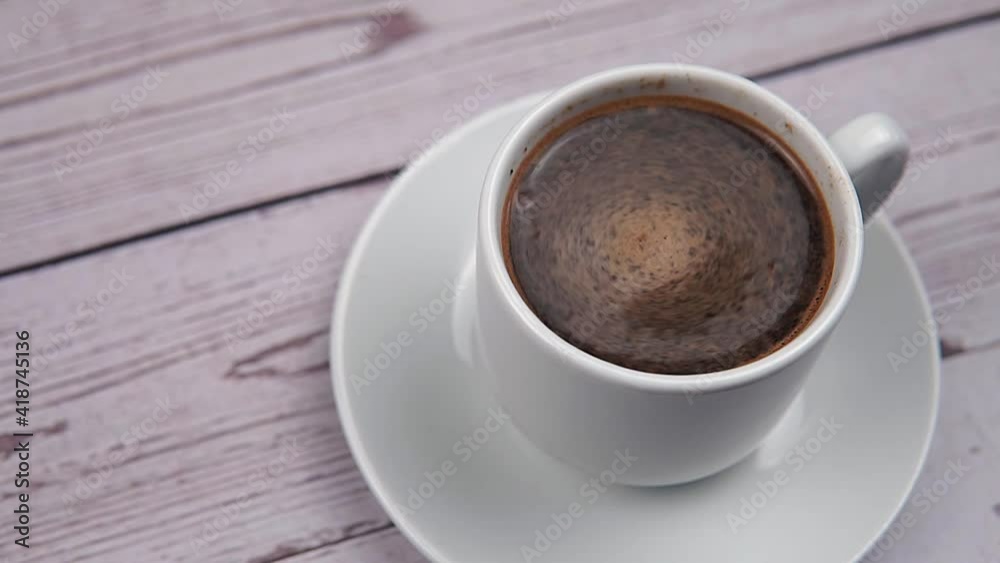 Swirl of foam in a white cup with coffee on wooden background Swirl of foam in a white cup with coffee on wooden background