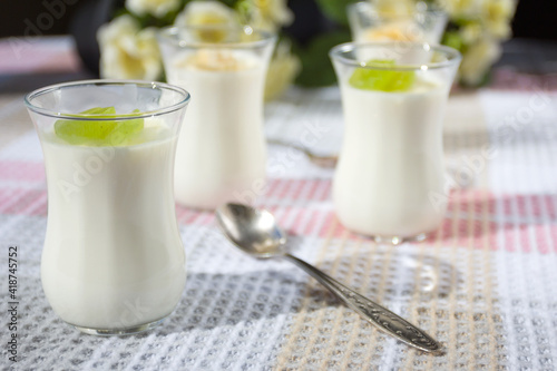 Italian dessert panna cotta in small transparent glasses decorated with grapes and banana on a checkered tablecloth