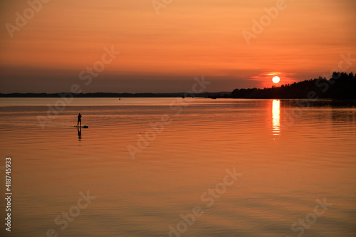 Ein Standuppaddler auf einem See im Sonnenuntergang