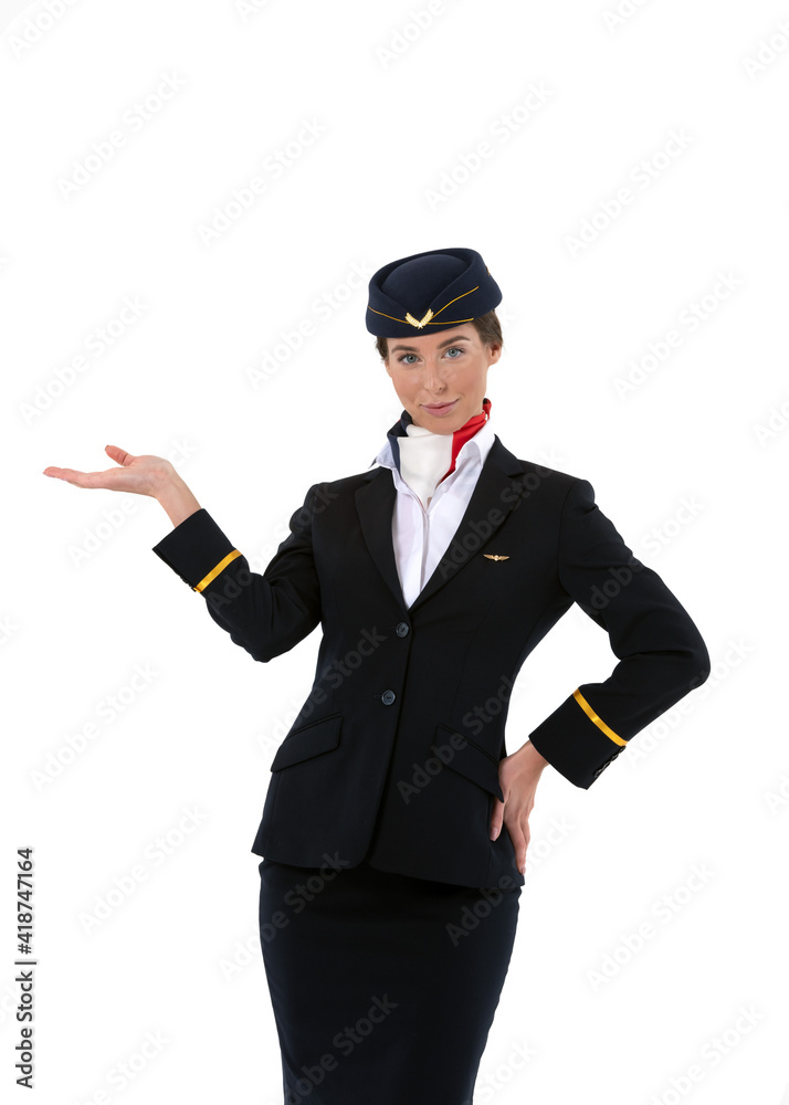 Beautiful young flight attendant standing and pointing towards something isolated on white background
