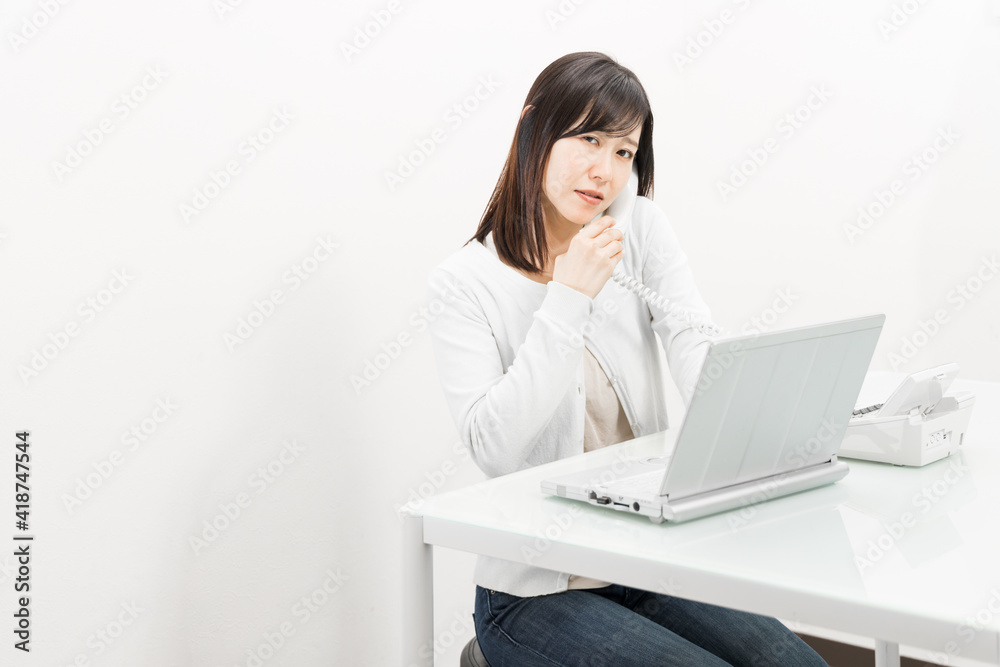 Woman talking on a landline while operating a PC Woman talking on a landline while operating a PC