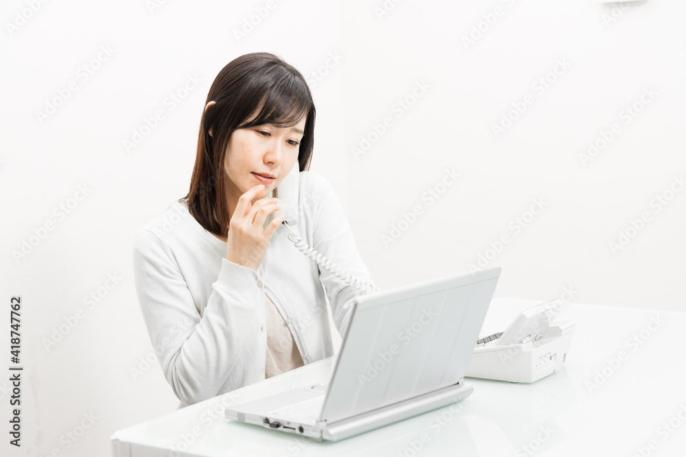 Woman talking on a landline while operating a PC Woman talking on a landline while operating a PC