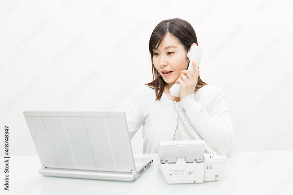 Woman talking on a landline while operating a PC Woman talking on a landline while operating a PC