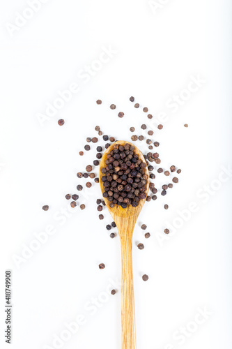 Black peppercorns (Black pepper) seeds in wooden spoon isolated on white background.