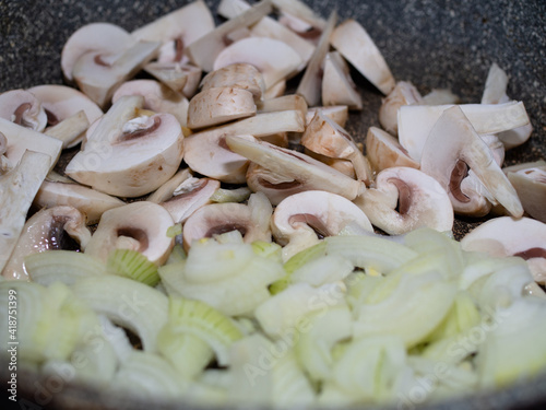 cut raw mushrooms in a frying pan with . cooking dinner.