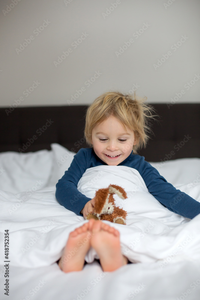 Cute child, lying in bed, playing with little stuff toy Cute child, lying in bed, playing with little stuff toy