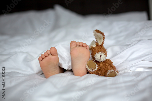 Cute child, lying in bed, playing with little stuff toy