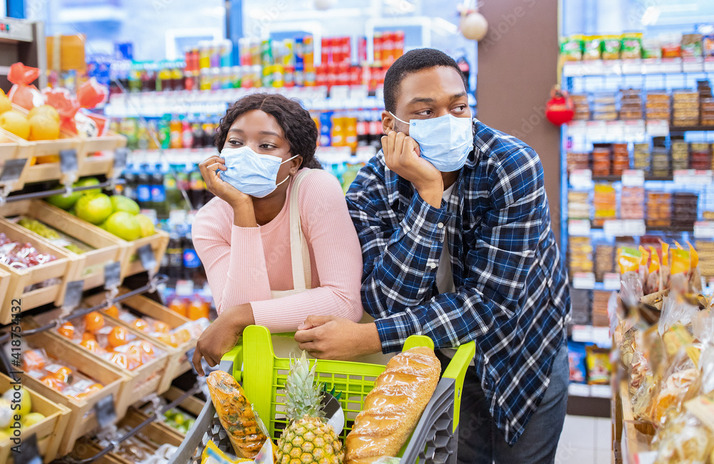 Black family in face masks buying food, tired of shopping for groceries at supermarket during covid-19 outbreak