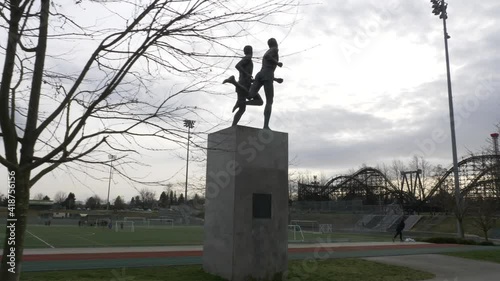 Hyperlapse shot of John Landy and Roger Bannister Miracle Mile bronze Statue in Vancouver. Soccer field and empire stadium. Track shot. photo