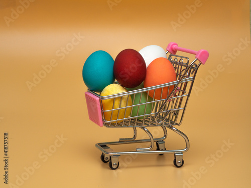 Several multicolored colored, boiled chicken eggs in a shopping cart (trolley). The concept of buying or selling decorated products and food for Easter.