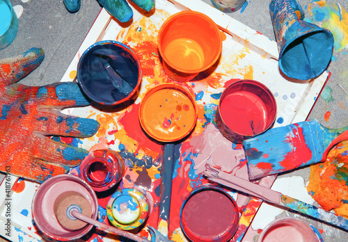 ulticolored paints mixed in different jars and cups, painter's tool photo